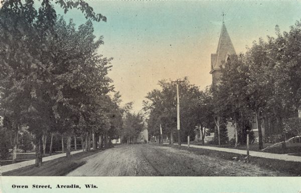 View looking down Owen Street. A church steeple i on the right, partly obscured by trees. Caption reads: "Owen Street, Arcadia, Wis."