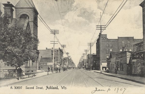 View looking down Second Street. Stores and other buildings line both sides of the street, including the Post Office on the left. Cable car tracks are running along the street.