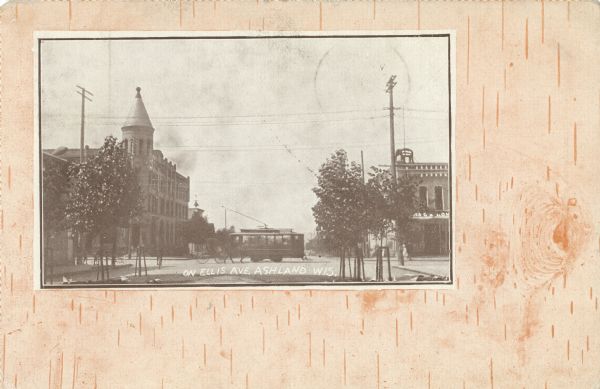 View of Ellis Avenue. A horse-drawn buggy is moving alongside a cable car down the road. Buildings and telephone poles line both sides of the street.The postcard has a simulated birch bark background.