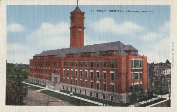 Exterior view of the front facade and grounds of the four-story, red brick St. Joseph Hospital.