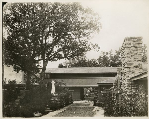 Taliesin I hayloft as seen from the courtyard. The statue, "Flower in a Crannied Wall," stands on a stone pillar. A cow and a calf can be seen through the passageway under the hayloft.