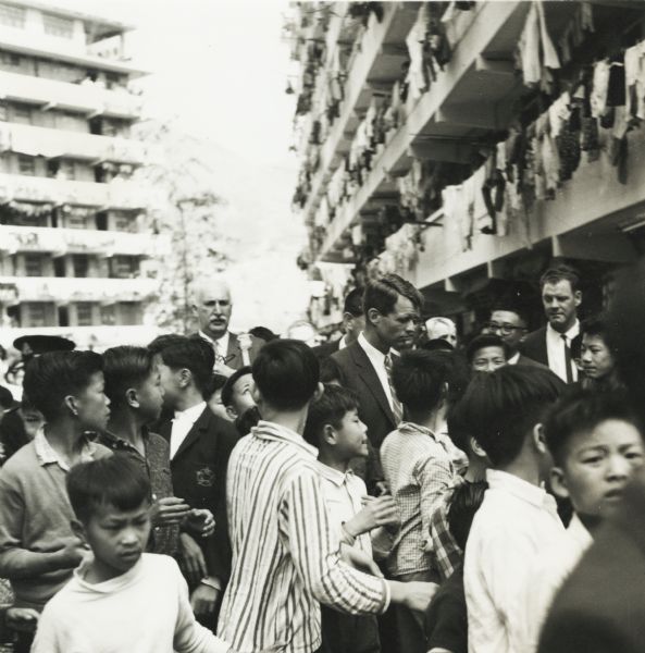 Robert Kennedy, then attorney general, surrounded by young people during a visit to Hong Kong. Kennedy was traveling in Southeast Asia, and the tall white-haired man with him is Cecil Brown, a journalist with NBC News.