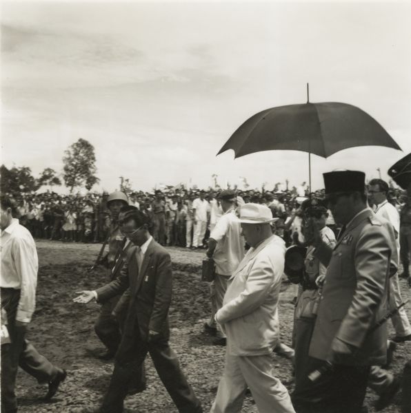 President Sukarno of Indonesia (under the umbrella) escorts Nikita Khruschev (in the white suit), visiting Soviet premier, to inspect some new construction.