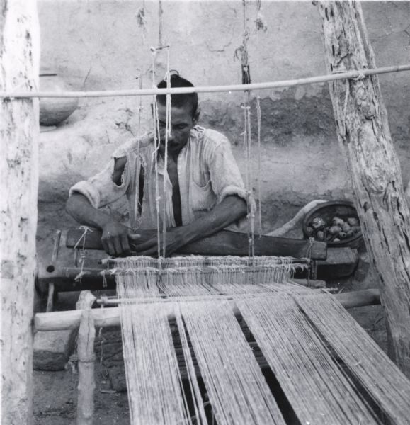A man seated at a loom in Jaipur, India.