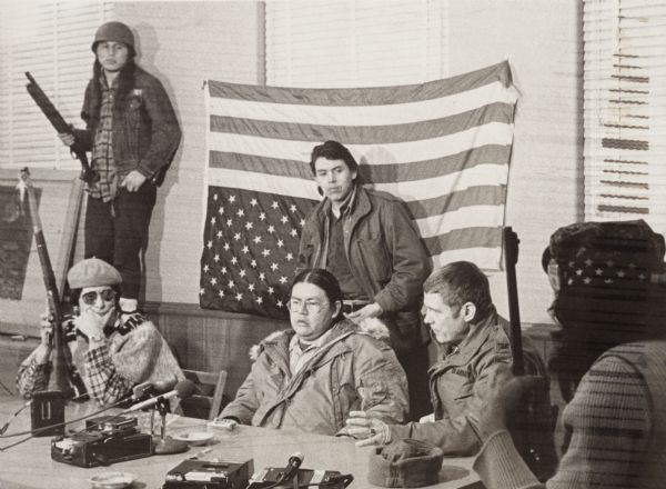 Negotiations between leaders of the Menominee Warrior Society and the American Indian Movement with General Hugh Simonson (in the Army jacket) of the Wisconsin National Guard during the seizure of the Alexian Novitiate at Gresham. The Native Americans are, standing: Melvin Chevalier and John Waubanascum; and seated, Dennis Banks of the American Indian Movement (AIM) and Michael Sturdevant.