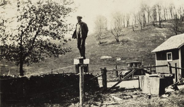Bernard Arms stands atop a post on a farm.