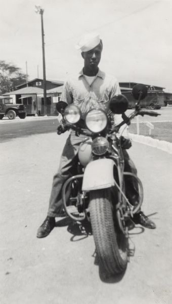 Lewis Arms sits on a motorcycle, probably at Barbers Point Naval Air Station near Pearl Harbor.