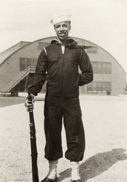 Lewis Arms poses in his Navy uniform holding a rifle on the day he graduated from the Great Lakes Naval Training Center.