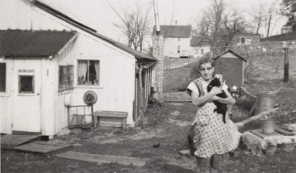 Nellie Arms, aunt of Lewis Arms, holds a cat outdoors at the farm she shared with her husband Bernard.