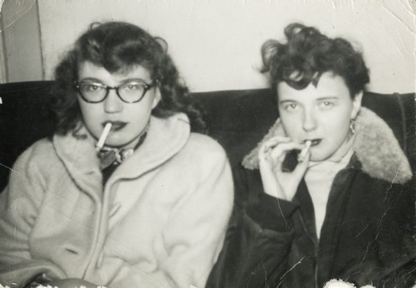 Carol Bank (left) and Barb (Flint?) Diggs, friends of Lewis Arms, sit together smoking cigarettes.