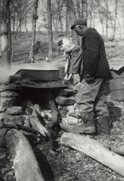 LuRay Arms and Otis Arms tending a fire while making maple syrup outdoors.