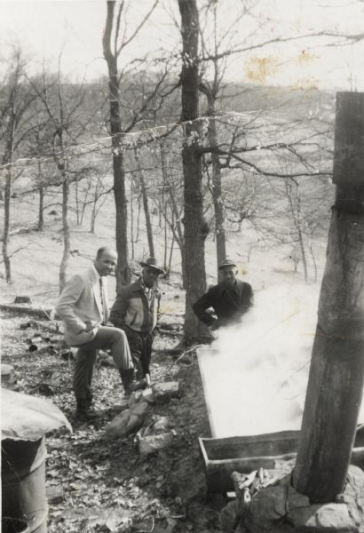 Three men from the Arms family making maple syrup outdoors. From left to right are: Lewis, Bernard, and Otis Arms.