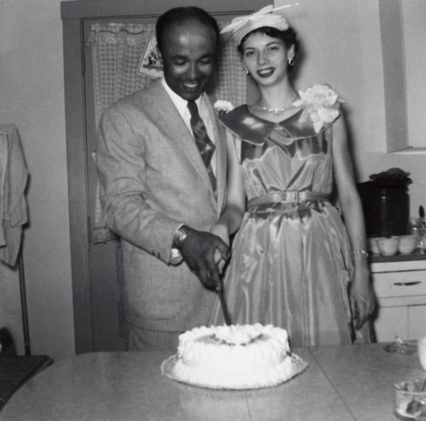 Lewis Arms and his new wife LuRay pose in their wedding clothes, cutting the wedding cake.