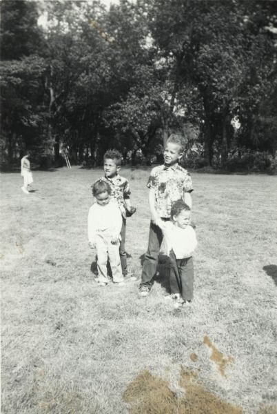 Four of the Arms children pose together. On the left, Craig Arms stands behind Rita Arms (Witter). On the right, Lewis Arms Jr. stands behind Mamie Arms.