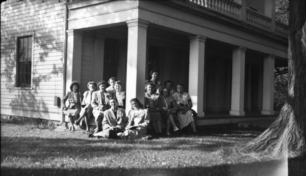 Visitors to the historic Charles A. Grignon House (built 1837-1839), probably during the 1940s. The visitors are seated on a corner of the front porch under the balcony, which was the most prominent aspect of the historic preservation work that took place in 1941. The house is now a museum operated by Outagamie County.