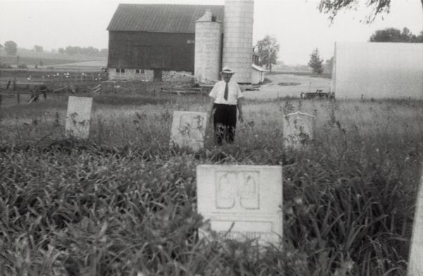 Local historian William F. Wolf visiting the Native American cemetery. In the background is a barn and a silo and other farm buildings.