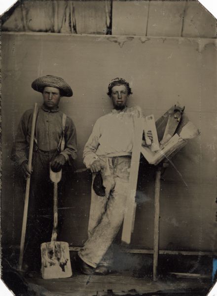 Tintype portrait (slightly tinted) of Isaac Wagner Acker (left) and an unidentified individual. Acker was born in 1837 in Whetstone, Crawford County, Ohio. He later settled in Stockbridge, Wisconsin and served in the 21st Wisconsin during the Civil War. At the time of his enlistment Acker gave his occupation as a mason, and the tools with which he and the other man are posed represent the construction trade.