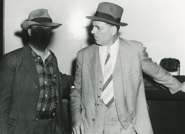 State Agent (left, with face blacked out to prevent future identification) as he seized the operator of the roulette table at the Ritz Bar after a sweeping raid on many Hurley area establishments. The arrest warrants were for gambling and prostitution.
