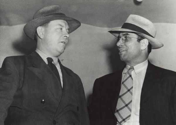 John W. Roach, Chief of the State Beverage Tax Division, (left) and Sheriff Sam Giovanoni, on right, snapped after a sweeping raid on many Hurley area establishments. The arrest warrants were for gambling and prostitution.