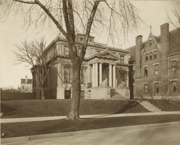 Exterior view from street of home of John Johnston (1836-1904), a successful Milwaukee banker, located at 645 Franklin Place, also known as "The Lion House."

The Lion House was built in 1851 for Edward Diedrichs. Shortly after his financial downfall in 1857, his friend Rudolph Pfeil purchased the home. Pfeil sold it to Henry Mann, manufacturer of chairs and wooden ware, who sold it to Johnston in 1896. Johnston added a second story.  In 1925 Mrs. Ethelinda (Thorsen) Johnston (1856-1947) added a garage to the left of the house.  This image predates the garage.  The Mary B. Hawley House seen on the right was built in 1896.