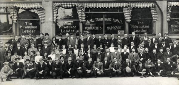 A large group portrait of people posing in front of "The Milwaukee Leader" newspaper established in December of 1911 by Victor L. Berger. He can be seen ten from the right in the second row. The paper ran until January of 1939, and was succeeded by the "Milwaukee Evening Post."
