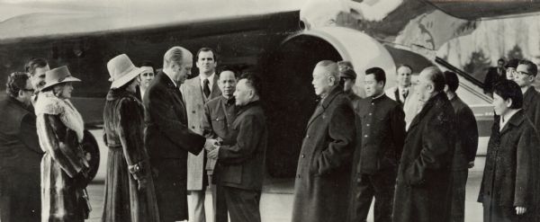 President Gerald Ford being officially greeted at the airport by Deng Xiao Ping. Mrs. Ford stands on the President's right; on the far left are Secretary of State Henry Kissinger and Ambassador George H.W. Bush, part of the official American delegation.