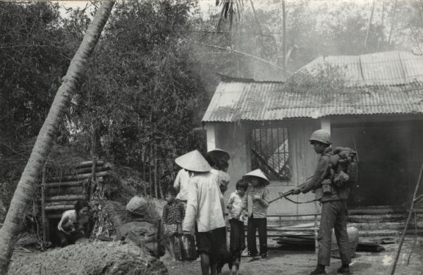 Vietnamese woman holding an infant emerging from a bomb shelter under the watchful eye of two South Vietnamese soldiers (ARVN). This incident was witnessed by American journalist Robert Shaplen shortly after the Tet offensive.