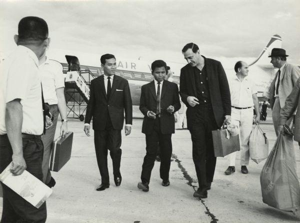 Robert Shaplen, the tall man with the briefcase, being greeted at an airport in Southeast Asia. Shaplen, who was regarded as the dean of the American journalists who covered that part of the world, was especially known for the many foreign affairs stories from Vietnam that he wrote for "The New Yorker" magazine. Shaplen's papers are part of the archival collections of the Wisconsin Historical Society.