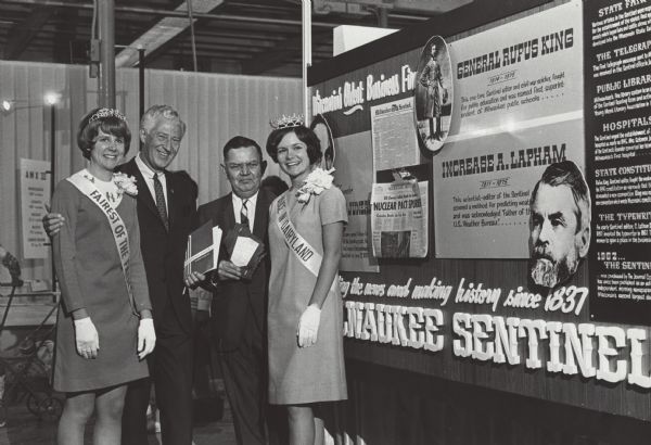 The Fairest of the Fair, Governor Knowles, an unknown man, and Alice in Dairyland pose at the "Milwaukee Sentinel" exhibit at the Wisconsin State Fair.