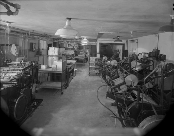 Wells Printing Company's new plant interior. Many pieces of letterpress equipment can be seen; presses and wheeled carts.