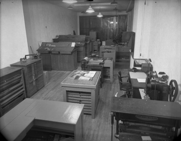 Wells Printing Company's new plant interior. There are many pieces of letterpress equipment; type cabinets, a composing stone with set type on it and a proof press.