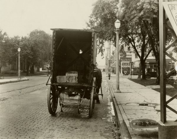 Oshkosh Pure Ice and Coal Co. horse-drawn wagon as seen from the back. Two blocks of ice are visible in the wagon. Note on back: Sept. 15, 1926-4:30 pm. Near corner Oregon & 11 st, #1, camera set pointing north toward wagon-rear of wagon was 28 feet distant = and 3 feet from curb.