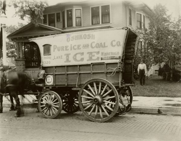 Oshkosh Pure Ice and Coal Co. horse-drawn wagon. Note on back: Near Oregon & 11st. #2, camera set pointing in an easterly direction and 26 ft. 4 in. west from east curb, man standing 23 feet east of east curb,  east wheel of wagon 3 feet west of east curb.
