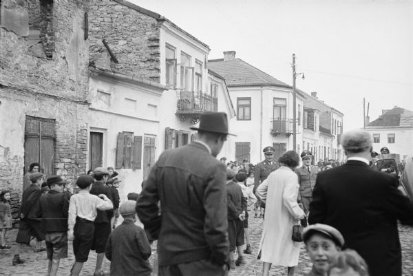 Street scene of people in the Jewish ghetto in Szydlowiec, Poland, being addressed by two German soldiers. The scene was witnessed by American journalist Alvin Steinkopf about one year after the German invasion.