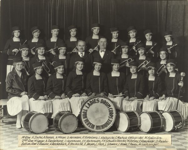 Women members and their Director of the Ladies Drum Corps posed in uniform with their instruments. Text on the bass drum, "Ladies Drum Corps, Turn Verein Milwaukee."