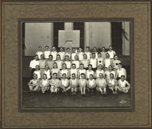Group portrait of men gymnasts from the Milwaukee Turners in a gymnasium. They are wearing uniforms.