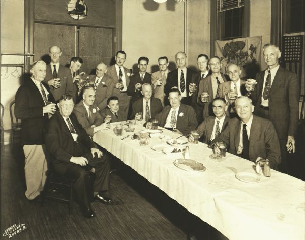 Group of men from the Milwaukee Turners, posing indoors, eating, drinking and smoking cigars. Text reads, “Bimbos. This solemn-faced group of swaffers of the amber brew is the fun club of the Milwaukee Turners."