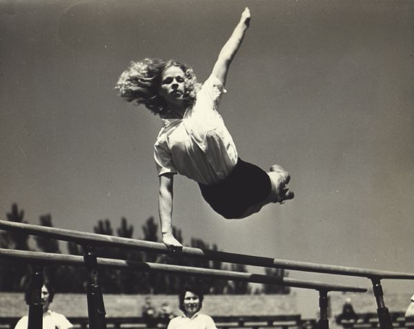 Hazel Sherman performing outside on the parallel bars at the Rufus King High School Stadium. The event was the Wisconsin State Turnfest.