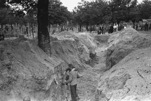 Digging for bodies in a mass grave near Lemberg, Poland, where German civilians were killed by the Poles during the Nazi invasion. American journalist Alvin Steinkopf was one of a contingent of journalists from neutral nations taken by the Germans to witness the scene.