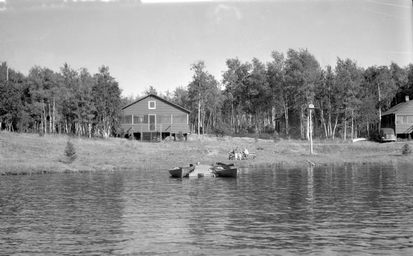 View from water of two men sitting on a bench near the shoreline of Upper Eau Claire Lake.