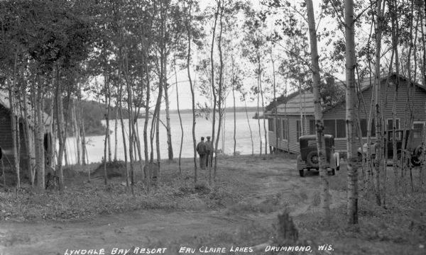 Two men standing near cabins looking at Upper Eau Claire Lake.