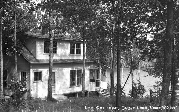 View down hill of two-story house on the shore of Cable Lake.
