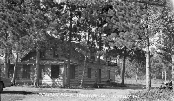 Two-story log building with a Grain Belt Beer/Hank's Inn sign at the Pinehurst Inn on Lower Clam Lake.
