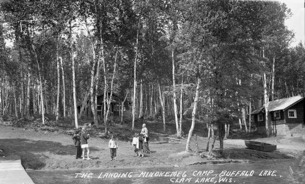 View from pier of group of children and a man on the sandy shore of Buffalo Lake.
