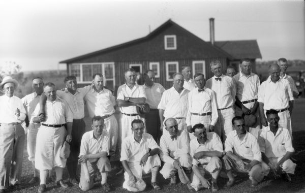 Twenty-one golfers posing in front of golf course clubhouse.