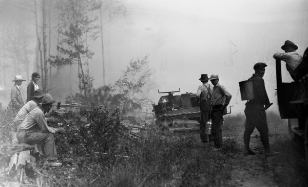 Men and one woman gathered around machinery in a cutover area of northern Wisconsin preparing to undertake an unknown task.