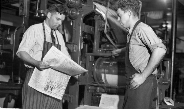 Two newspaper pressmen reviewing the newspaper print at the Ashland Daily Press.
