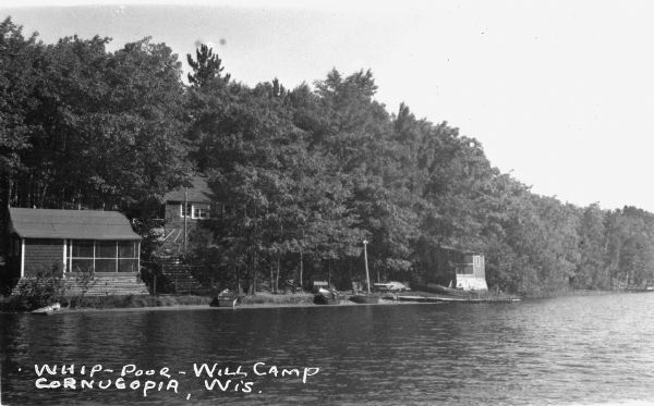 View from water of cabins and boats near shoreline of inland lake.