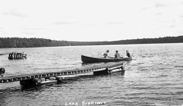 Three women in a rowboat off a dock on Siskiwit Lake.