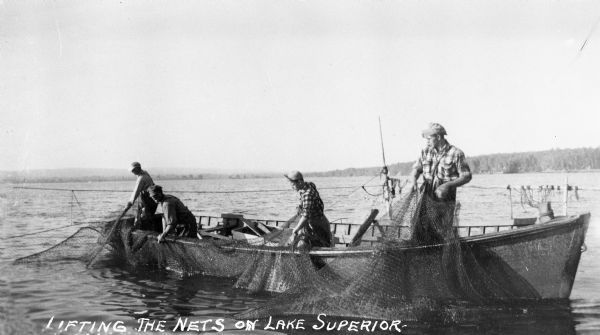 Four men in a large row boat lifting fishing nets on Lake Superior near Cornucopia.